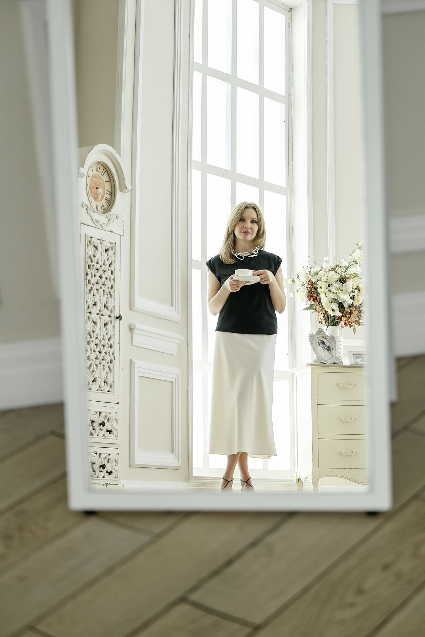 Une femme élégante, une boisson chaude à la main, dans un intérieur blanc