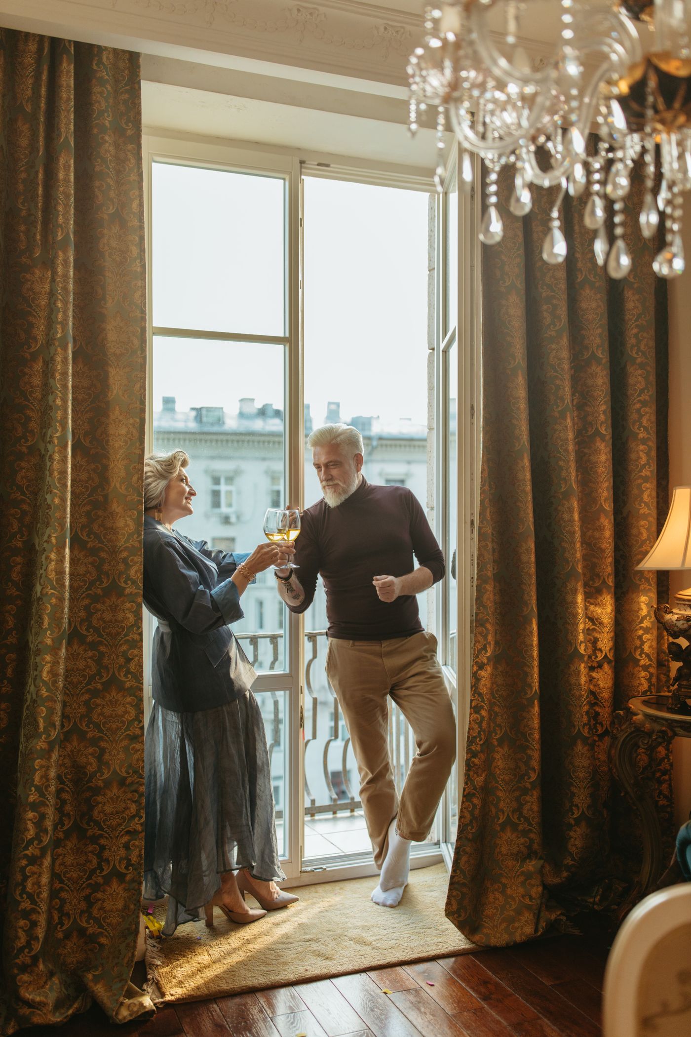 Un couple senior trinque en riant dans un salon lumineux