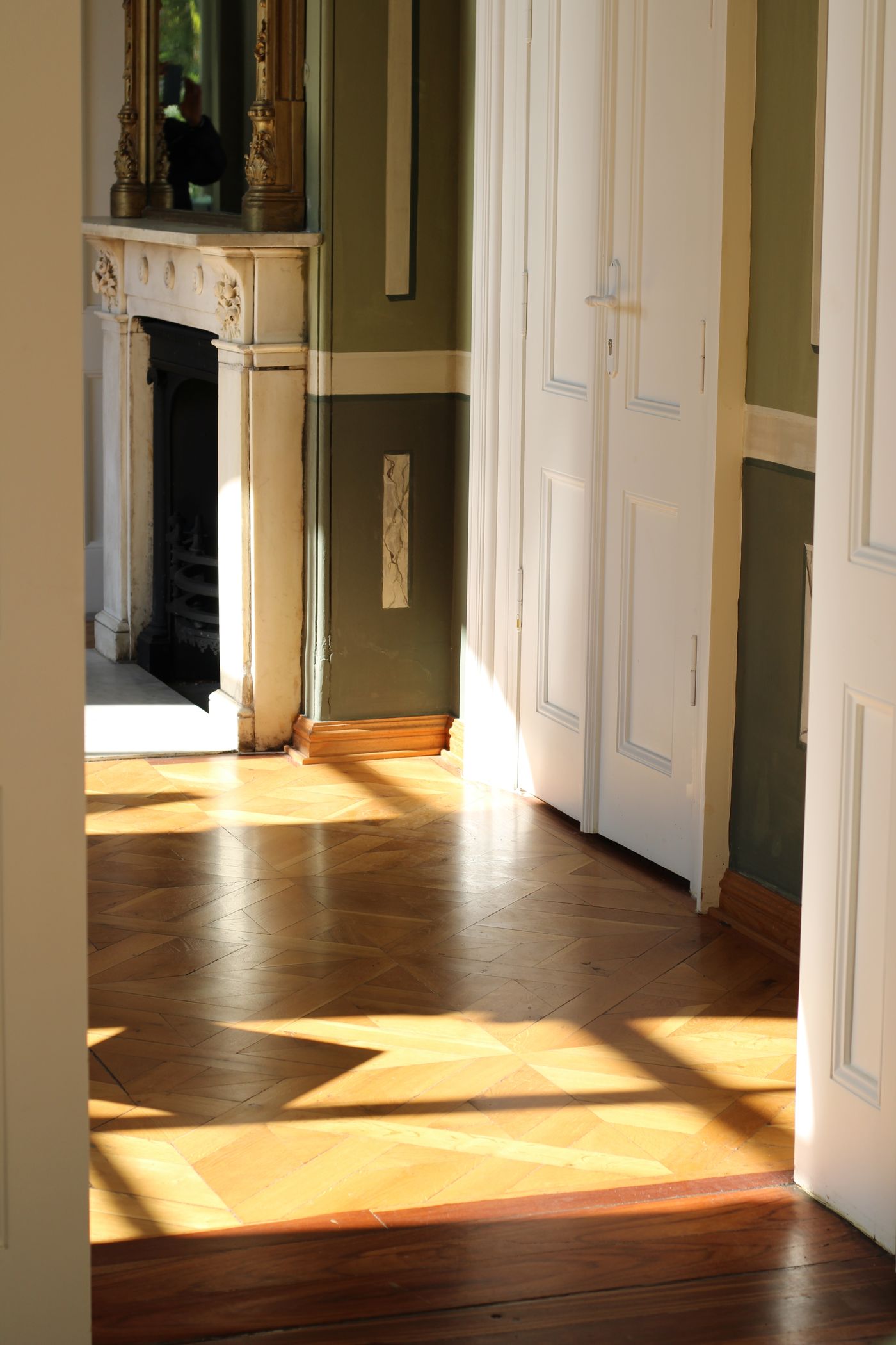 Enfilade d'un appartement ancien, portes hautes et lumière du matin sur le parquet